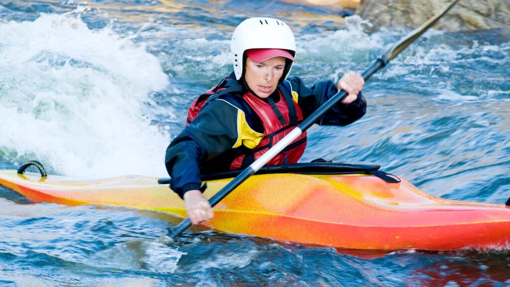 Beginner kayaking woman wearing helmet and life jacket